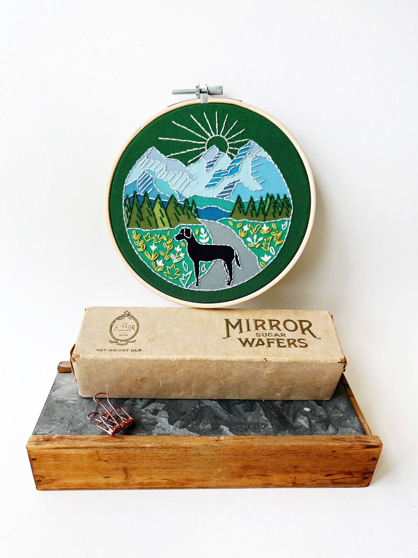 Embroidery hoop with nature-themed design on a box of Mirror Wafers.